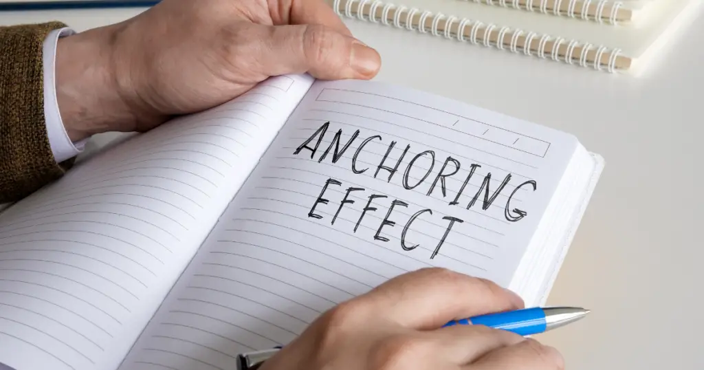 Hands on a notepad with anchoring effect written on it