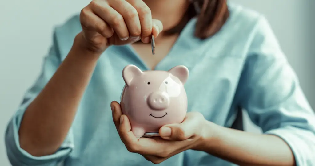 Woman dropping a coin into a piggy shaped bank