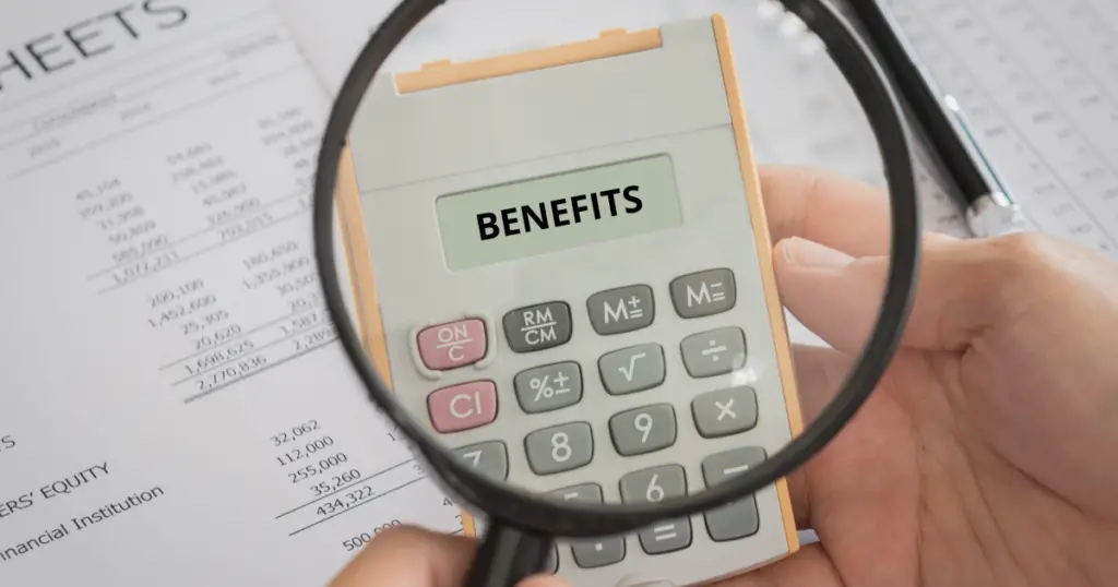 Looking through a magnifying glass at a calculator with the words benefits on the display