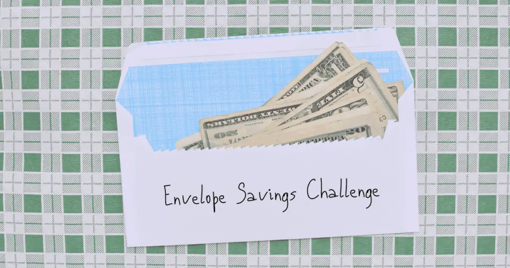 US dollars in a white envelope that says Envelope Savings Challenge on it with a green and white checkered background
