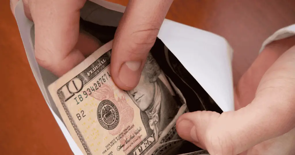 Hand pulling a $10 bill out of an envelope
