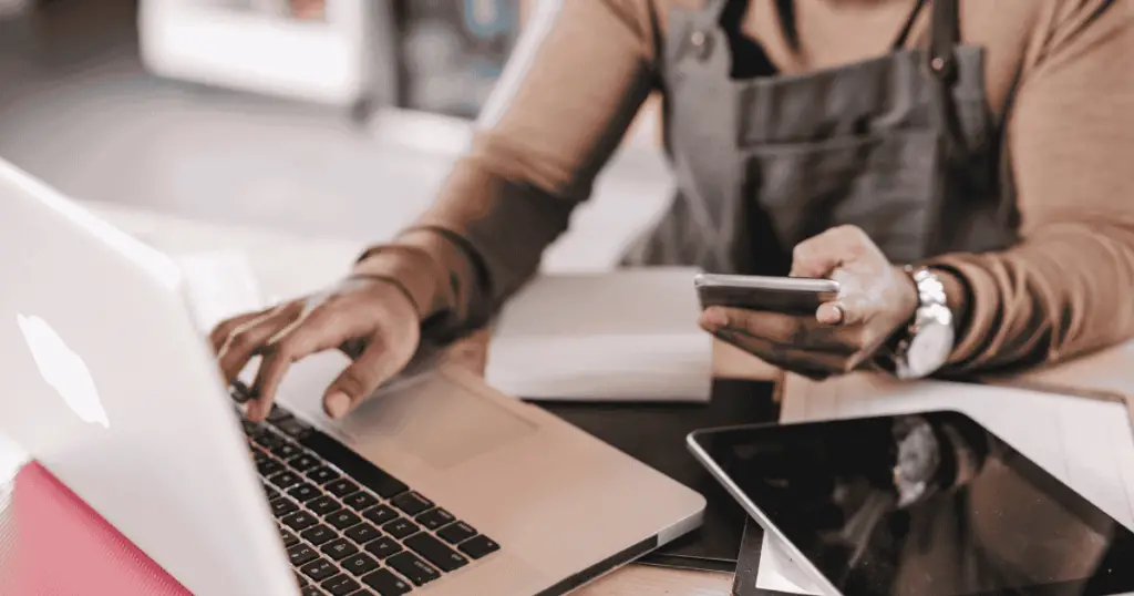Person looking at a phone and a laptop